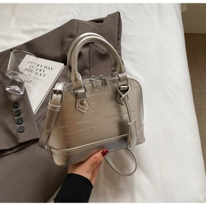 Detail of silver textured shell bag with metal zipper and adjustable strap handles