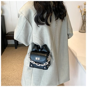 Detailed close-up of a black mini box bag with oversized bow and silver chain strap