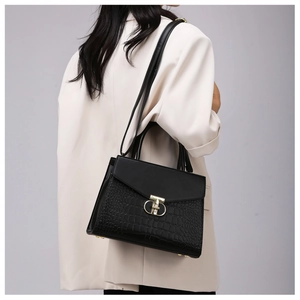 Detail view of black crocodile pattern texture and gold metal lock on luxury handbag