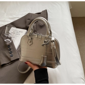 Chic silver shell bag with crocodile texture on a white background with styling accessories