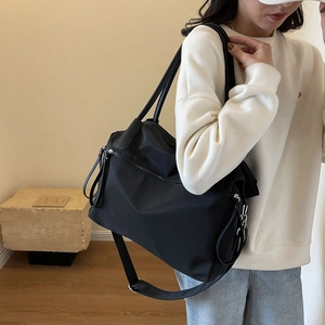 Detail of black nylon tote bag with wide canvas strap and premium leather handles
