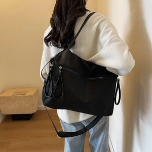 Detailed view of black canvas tote bag with nylon texture and leather strap accents