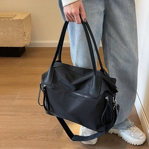 Detail of a black large-capacity canvas tote bag with nylon texture and leather trim