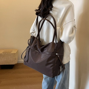Detail of a dark brown large capacity canvas tote bag featuring front metal zipper design