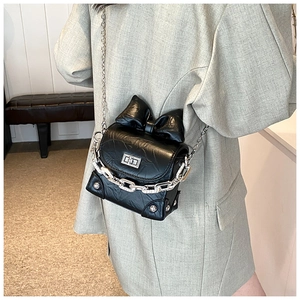Detailed back view of a black mini bow crossbody bag with silver chain on a model