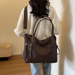 Detail of dark brown canvas tote bag with leather handles and detachable shoulder strap