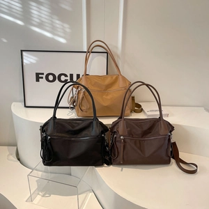Detailed view of three nylon tote bags in black, yellow and brown on display