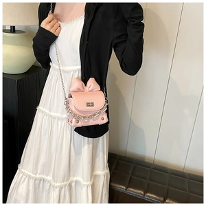 Pale pink mini bow box bag with silver chain strap shown worn by a model in detail