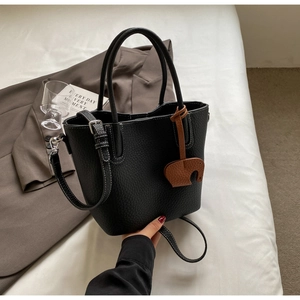 Close-up of black lychee grain leather bucket bag with contrast stitching and elephant charm