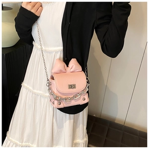 Detailed view of pink bow box bag with silver chunky chain on a white dress model