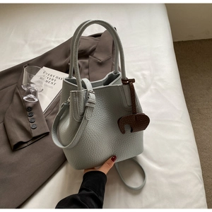 Detail of light blue lychee pattern leather bucket bag with cute elephant charm