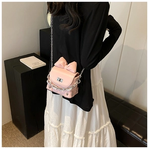 Close-up of pink mini box bag featuring a leather bow, silver chain, and twist lock detail