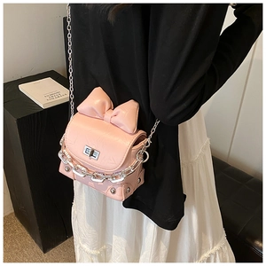 Detail view of pink bow box bag featuring a silver twist lock and metal chain strap