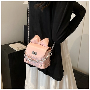 Detailed side view of pink mini bow crossbody bag with silver chain worn by a model