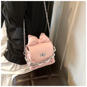 Detailed view of pink bow box bag with silver chain strap worn by a model