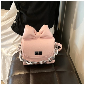 Close-up of pink mini crossbody bag featuring a large bow and silver chain strap