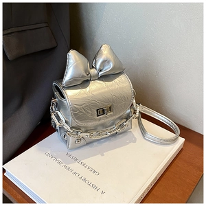 Close-up of metallic silver mini box bag with large bow and punk metal chain detail