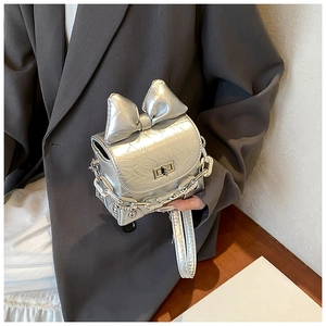 Detail of silver bow crossbody bag with metallic fold texture and turn-lock closure