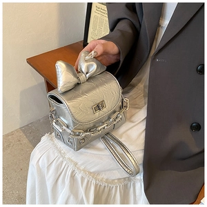 Detail of silver mini bow box bag with metallic texture and sleek chain strap for women