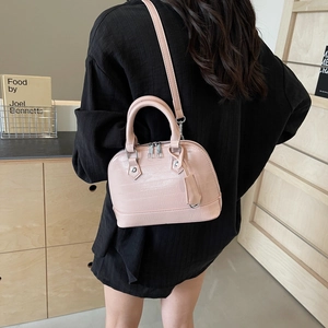 Pink faux crocodile leather shell bag with top handles and silver zippers shown on a model