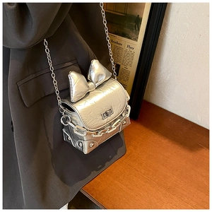 Detail of silver metallic mini box bag with bow decoration and crinkled texture