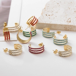 Macro view of C-shaped gold-plated earrings with multi-colored round cubic zirconia studs