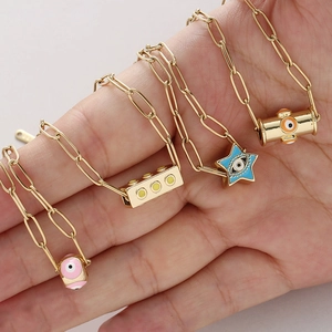 Détail des pendentifs œil porte-bonheur sur une chaîne trombone dorée