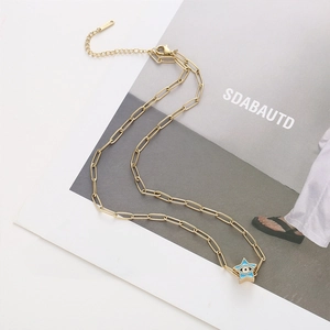 Détail d'un collier chaîne trombone doré avec pendentif étoile œil bleu sur un livre