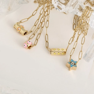 Détails de pendentifs étoile et œil émaillés sur des chaînes dorées de style bohème