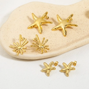 Detailed view of three gold-plated starfish earrings with unique textures on a ceramic tray