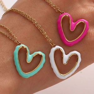 Detail of three colorful enamel heart pendants in mint green, white, and rose pink tones