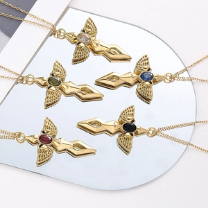 Detail of five gold angel sword necklaces with colorful oval crystals on a mirror surface
