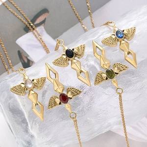 Detail of angel sword wing pendants with colorful gemstones on a glass background