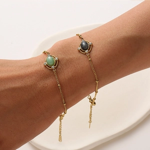 Close-up of titanium steel gold bracelets with green and grey natural stones on white tray
