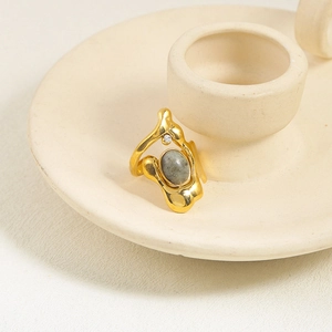 Detail of irregular gold lava ring with grey-green oval gemstone and sparkling crystal
