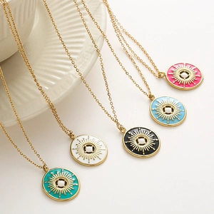 Détail de pendentifs soleil en émail coloré sur chaînes dorées aux couleurs vives