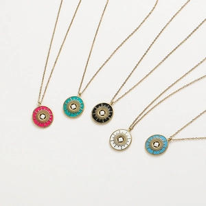Cinq colliers avec pendentifs soleil en émail coloré et finition dorée sur fond blanc