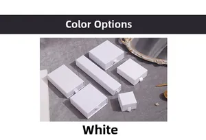 Multiple sizes of white drawer-style jewelry boxes with ribbon pull tabs on fabric background