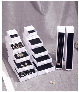 Detail of white sliding drawer jewelry boxes with black velvet lining and ribbon pulls