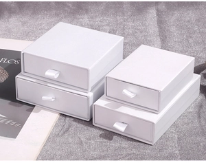 Detail of white textured drawer gift boxes with silk ribbons and premium cardboard finish