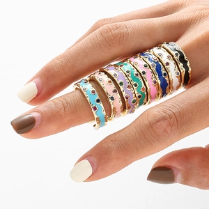 Lot de 9 bagues colorées en émail doré avec petites pierres précieuses sur la main