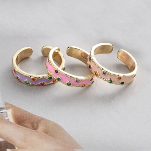 Détail de trois bagues ajustables en émail coloré et zircons finition dorée