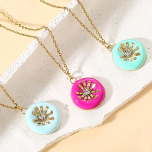 Close-up of three colorful enamel sunflower pendants with gold chains and rhinestones