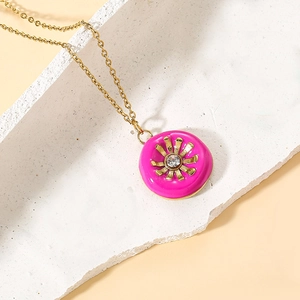 Detail of a rose pink enamel donut pendant necklace with a golden sunburst design