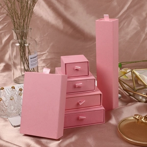 Pink drawer jewelry box set with ribbon handles displayed on elegant silk fabric