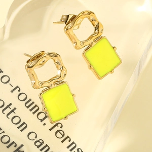 Close-up of geometric square drop earrings with gold plating and neon yellow inlay details