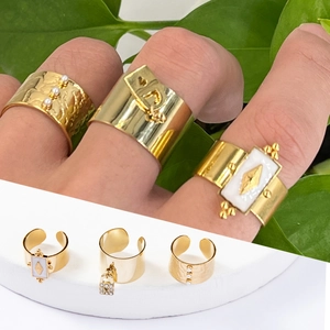 Détails de trois bagues dorées avec perles, pendentif cadenas et incrustation blanche
