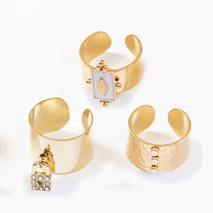 Gros plan de bagues dorées vintage avec perles, strass et détails de texture martelée