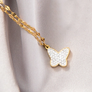 Vue macro d'un pendentif papillon doré avec zircons sur un tissu en velours gris