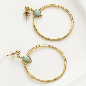 Detalle de pendientes de aro dorados vintage con piedra verde y borde granulado